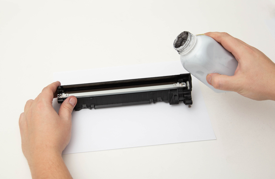 Refilling toner in a laser printer cartridge on a white background. Copy space for text